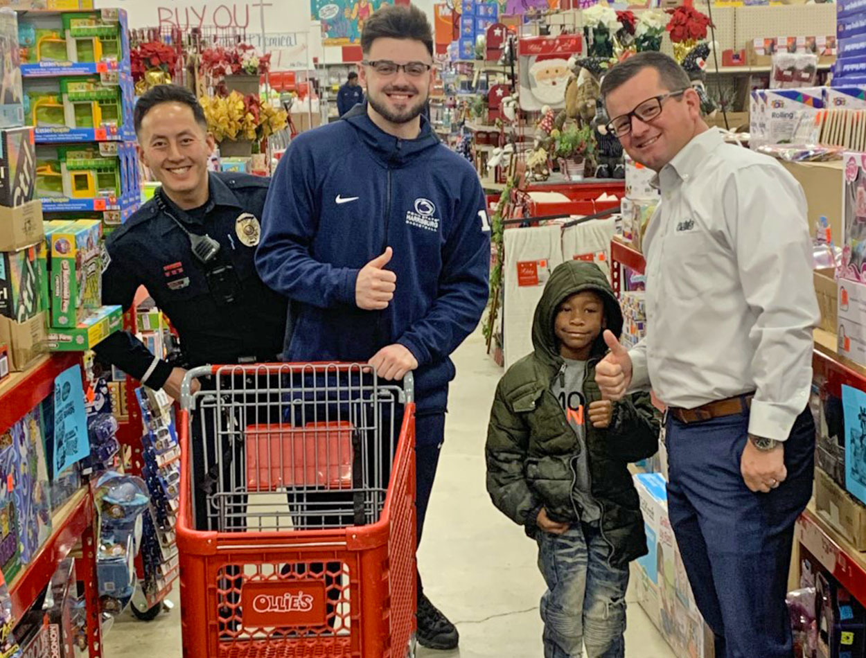 donald friday jr. with police officers and a local child at the 2022 shop with a cop holiday event