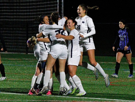 women's soccer players celebrate with each other after scoring a goal in a playoff game in 2023